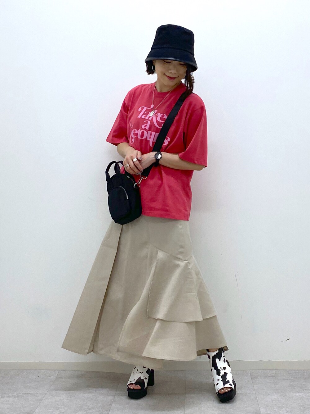 ベージュ系のスカート、ホワイト系のサンダル、ブラック系のショルダーバッグを着用したレディースの春コーディネートの2枚目の写真