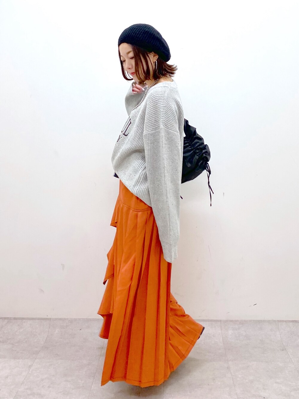 グレー系のニット/セーター、オレンジ系のスカート、ブラック系のローファーを着用したレディースの冬コーディネートの5枚目の写真
