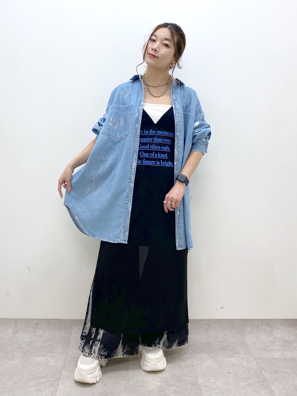 ブラック系のデニムパンツ、ホワイト系のスニーカー、ブラック系のワンピースを着用したレディースの春コーディネートの9枚目の写真