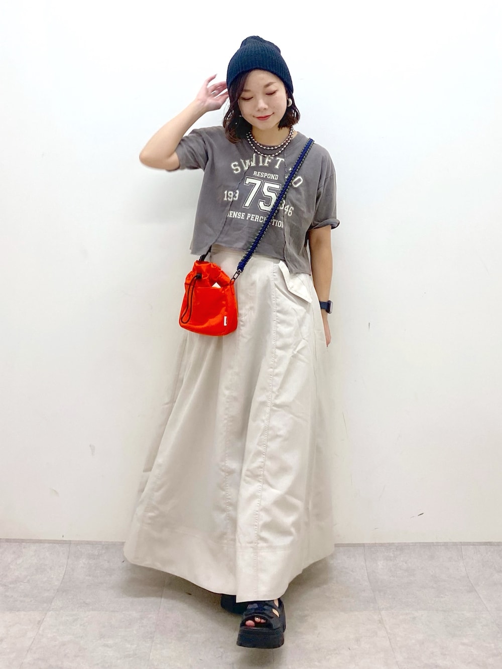 ブラック系のTシャツ/カットソー、オレンジ系のショルダーバッグ、ベージュ系のスカートを着用したレディースの夏コーディネートの4枚目の写真