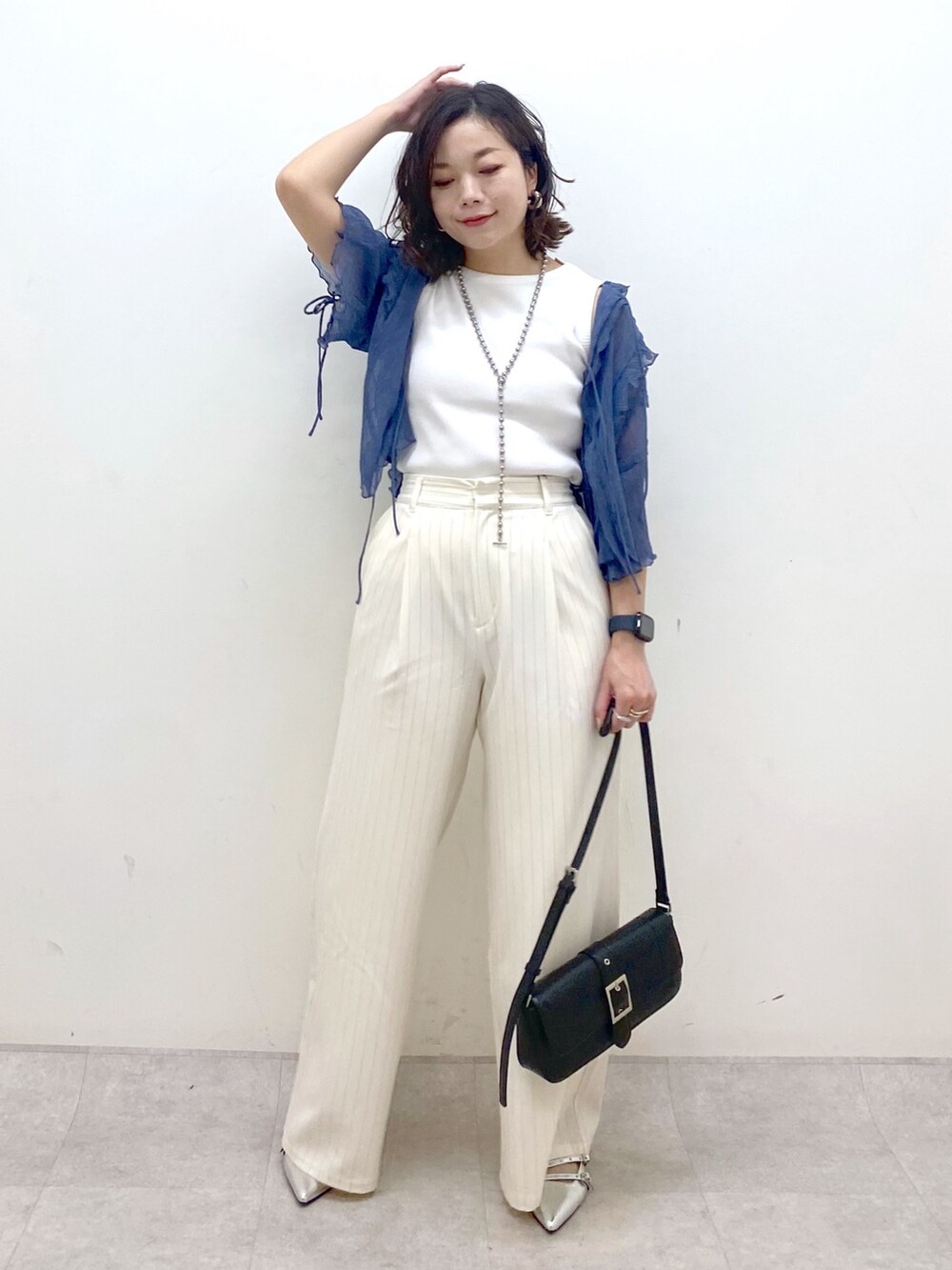 ホワイト系のスラックス、ブラック系のハンドバッグ、シルバー系のパンプスを着用したレディースの夏コーディネートの9枚目の写真