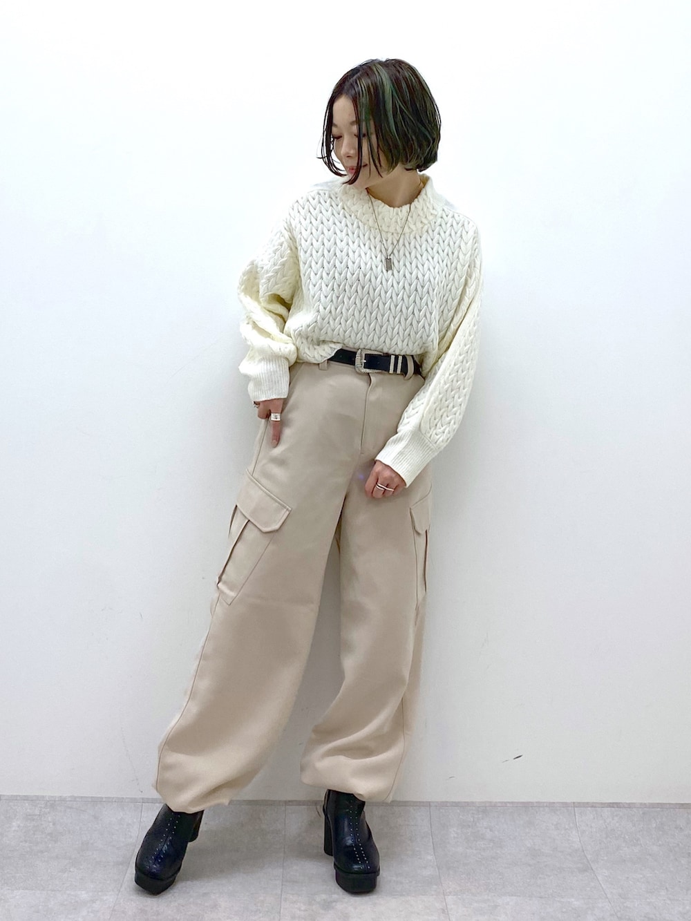ベージュ系のカーゴパンツ、ホワイト系のニット/セーター、ブラック系のブーツを着用したレディースの冬コーディネートの2枚目の写真