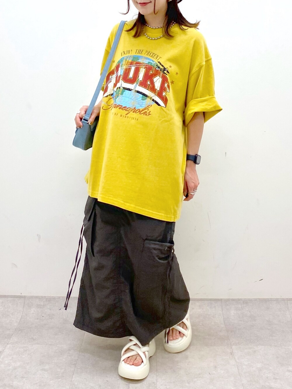 グレー系のスカート、ホワイト系のサンダル、ブルー系のハンドバッグを着用したレディースの春コーディネートの3枚目の写真