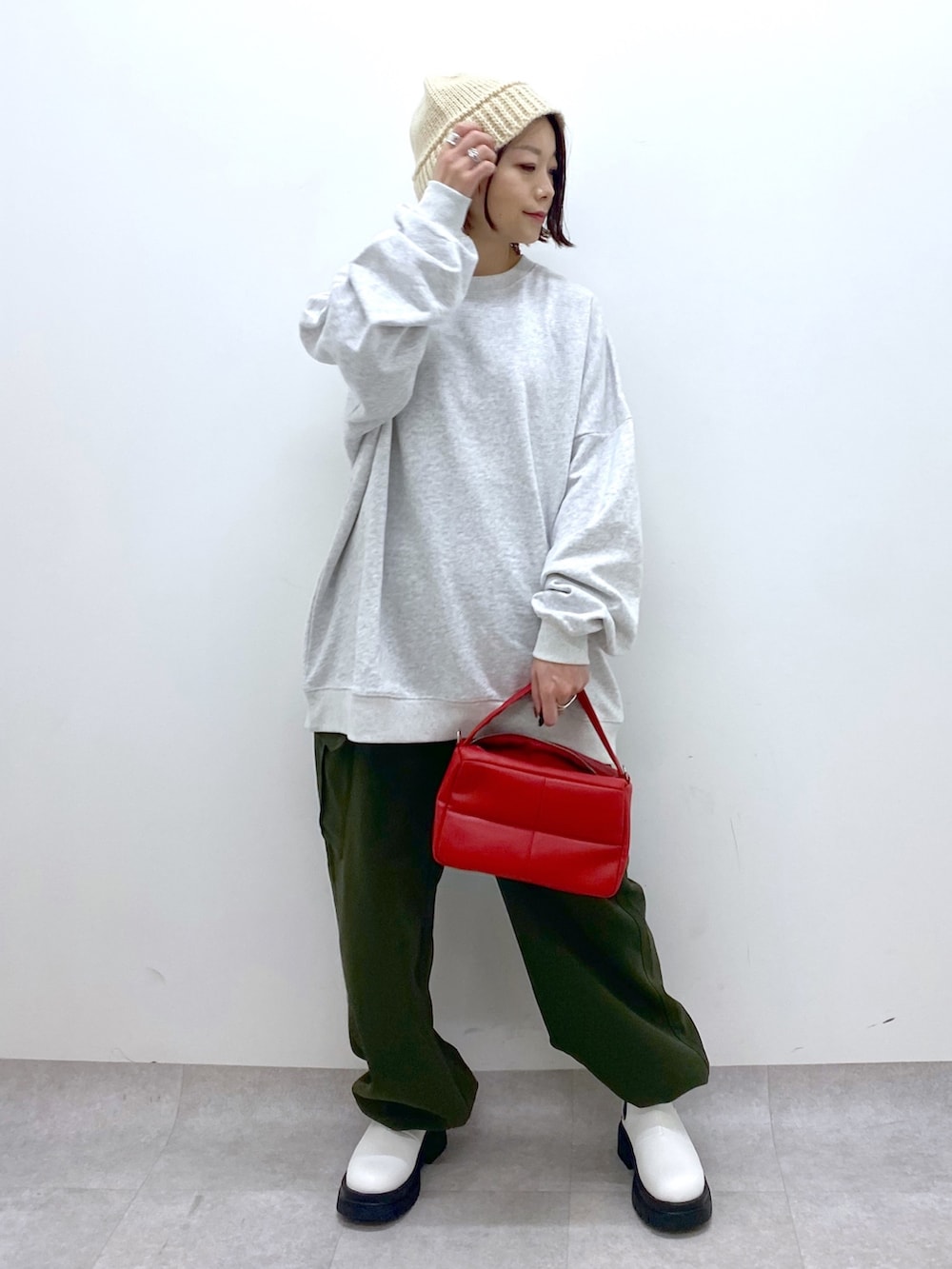 グレー系のトップス、レッド系のショルダーバッグ、ホワイト系のシューズを着用したレディースの秋コーディネートの5枚目の写真