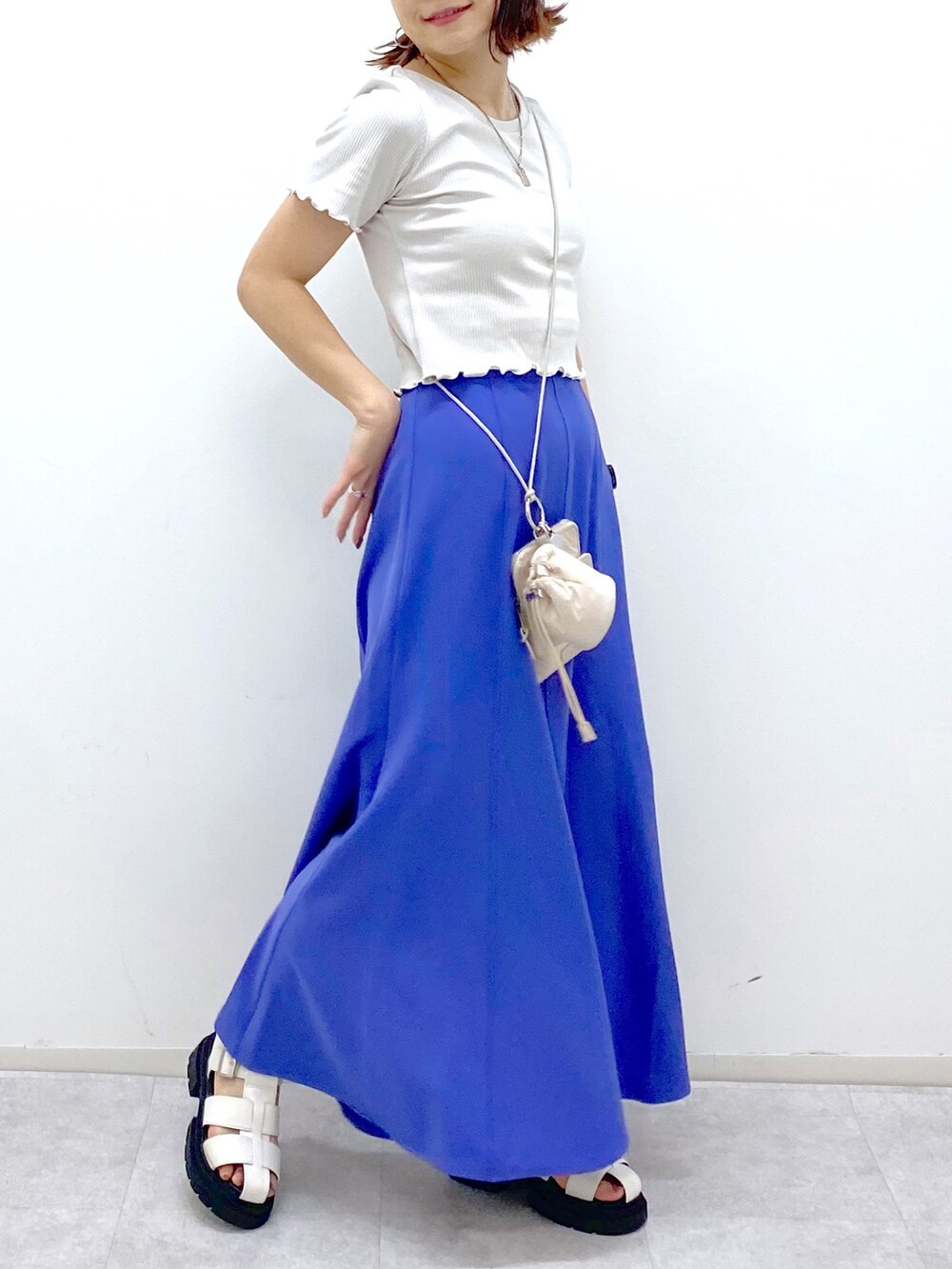 グレー系のトップス、ブルー系のスカート、ベージュ系のショルダーバッグを着用したレディースの夏コーディネートの5枚目の写真