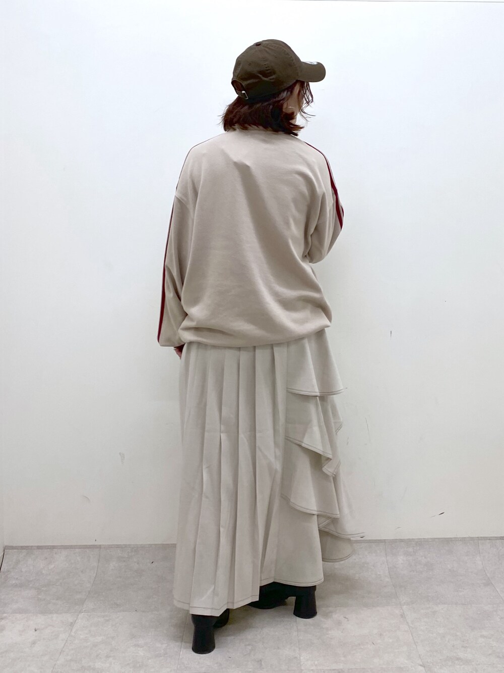 ベージュ系のスウェット、グレー系のスカート、ブラック系のブーツを着用したレディースの秋コーディネートの5枚目の写真