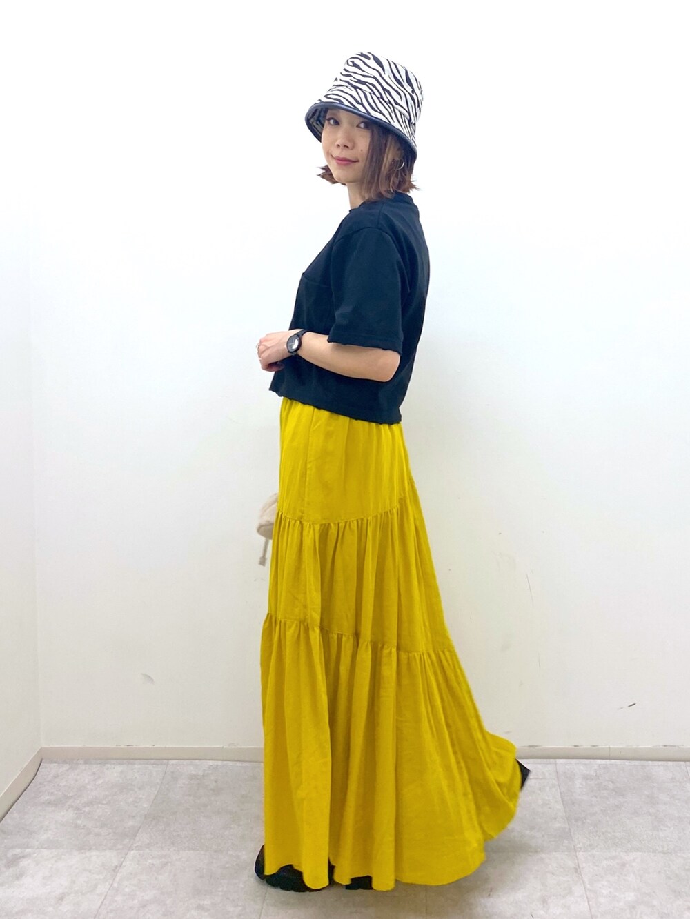 ブラック系のトップス、イエロー系のスカート、ベージュ系のショルダーバッグを着用したレディースの夏コーディネートの5枚目の写真