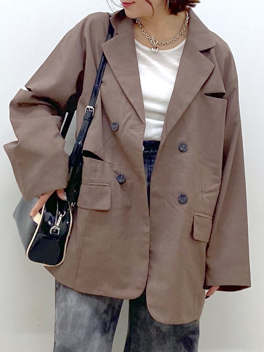 ブラック系のデニムパンツ、ブラック系のスニーカー、ブラウン系のテーラードジャケットを着用したレディースの秋コーディネートの2枚目の写真