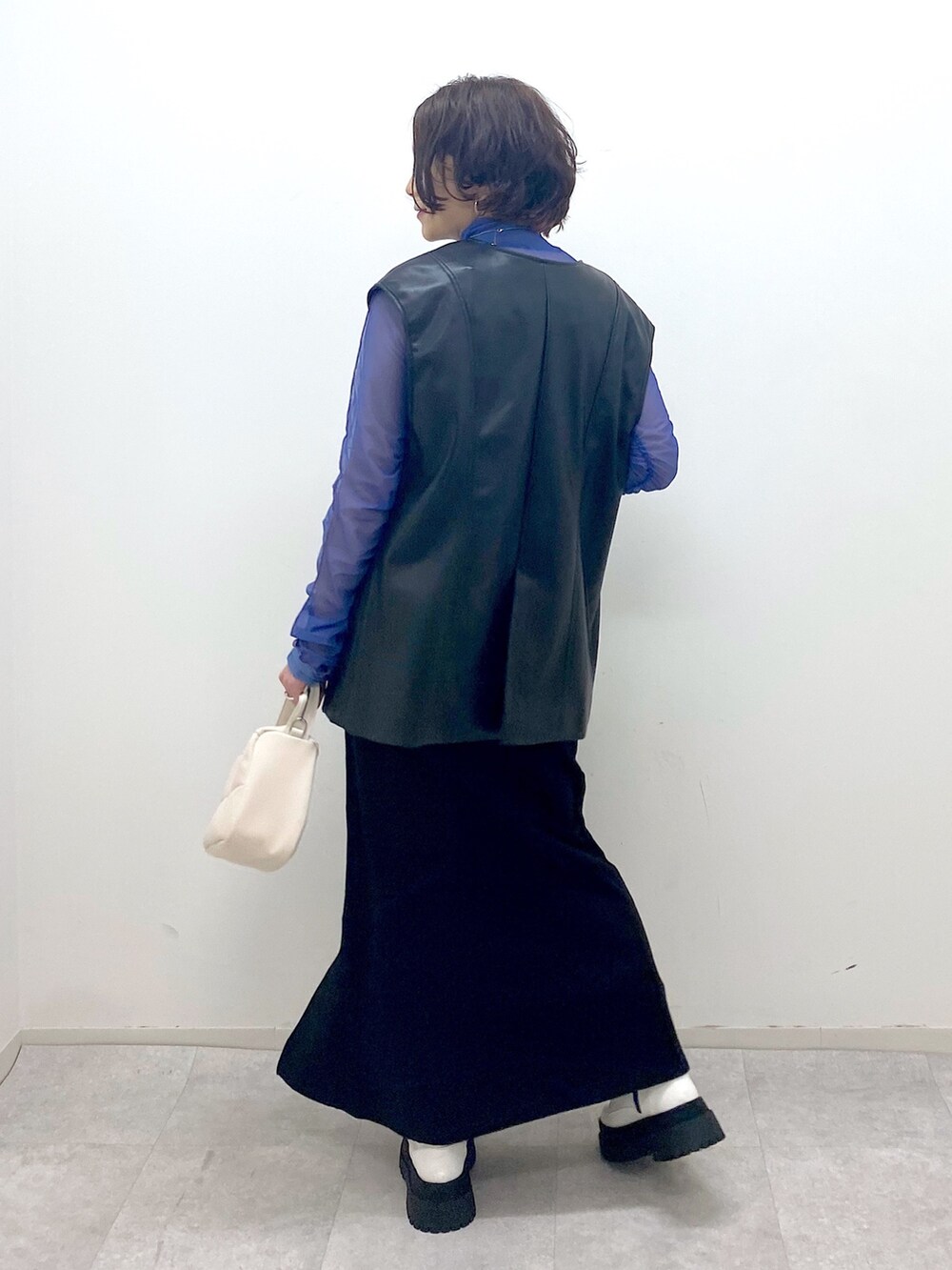 ブラック系のその他アウター、ブラック系のスカート、ホワイト系のショルダーバッグを着用したレディースの秋コーディネートの3枚目の写真