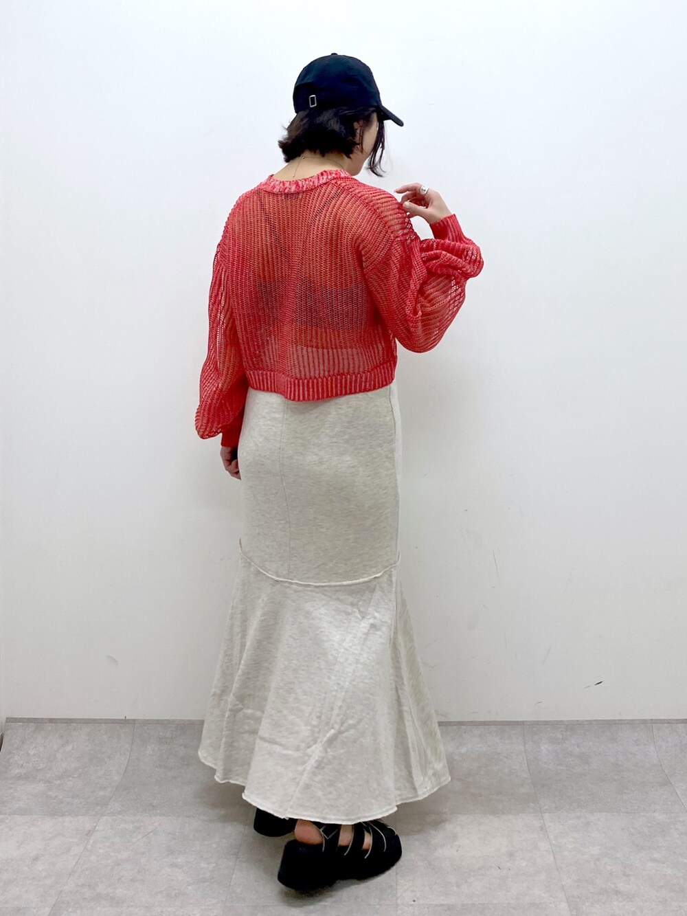 ベージュ系のスカート、レッド系のカーディガン/ボレロ、ブラック系のサンダルを着用したレディースの春コーディネートの3枚目の写真