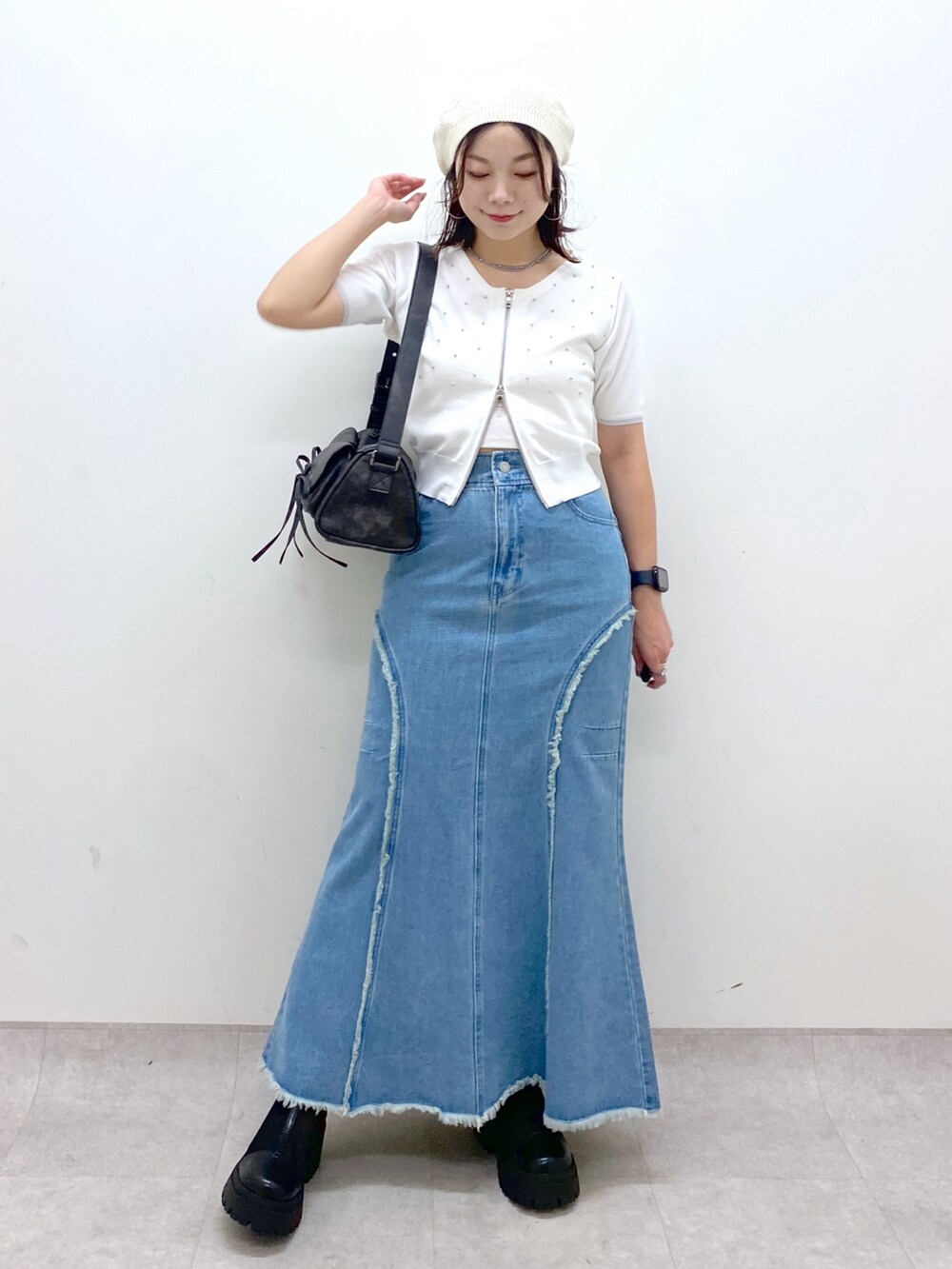 ブルー系のデニムスカート、ホワイト系のニット/セーター、ブラック系のショルダーバッグを着用したレディースの夏コーディネートの9枚目の写真