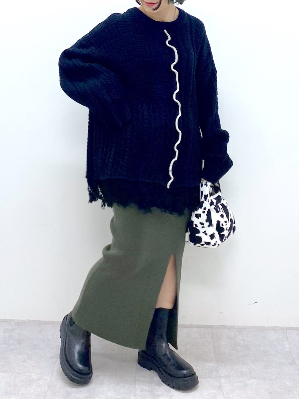 ブラック系のトップス、グリーン系のスカート、ブラック系のバッグを着用したレディースの冬コーディネートの5枚目の写真