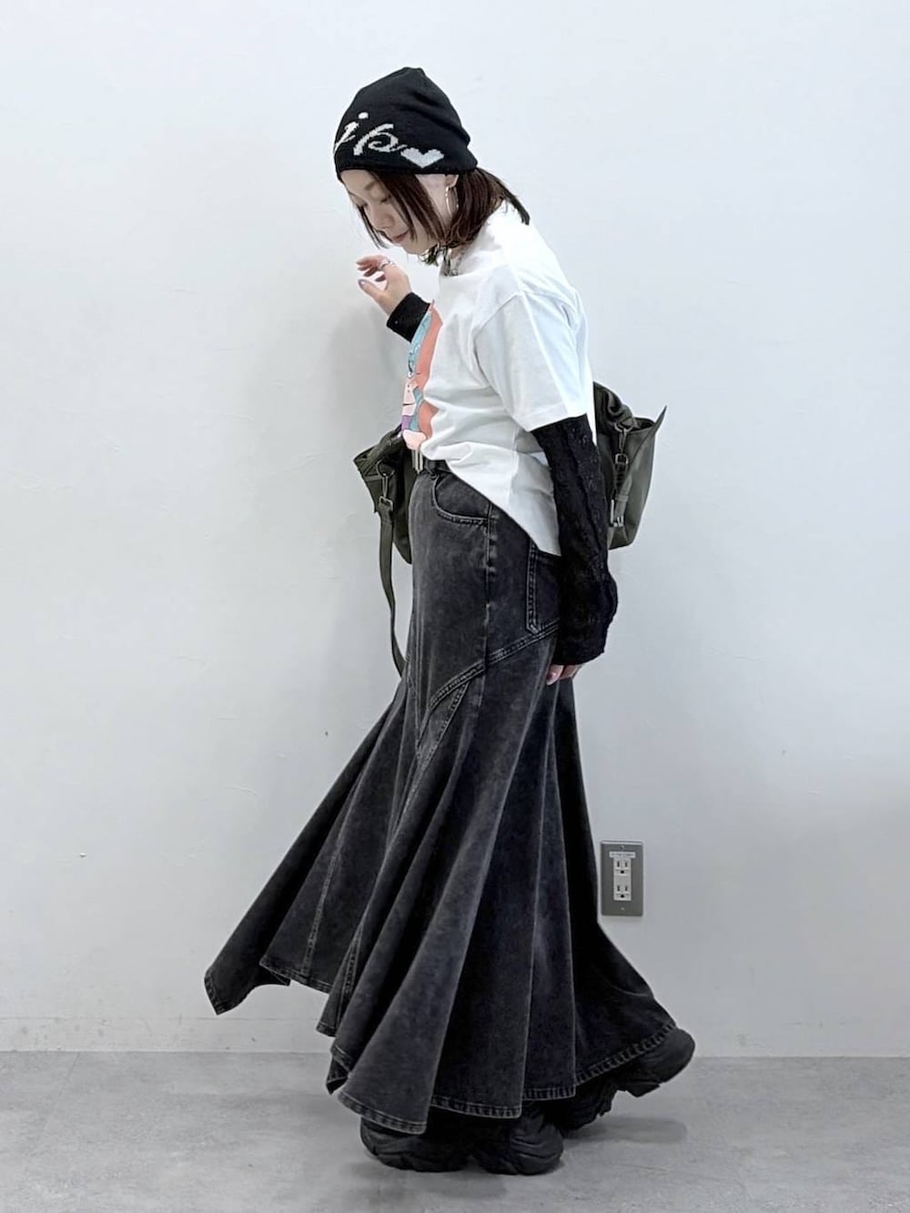 ブラック系のスニーカー、グリーン系のボストンバッグ、ブラック系のデニムスカートを着用したレディースの春コーディネートの6枚目の写真