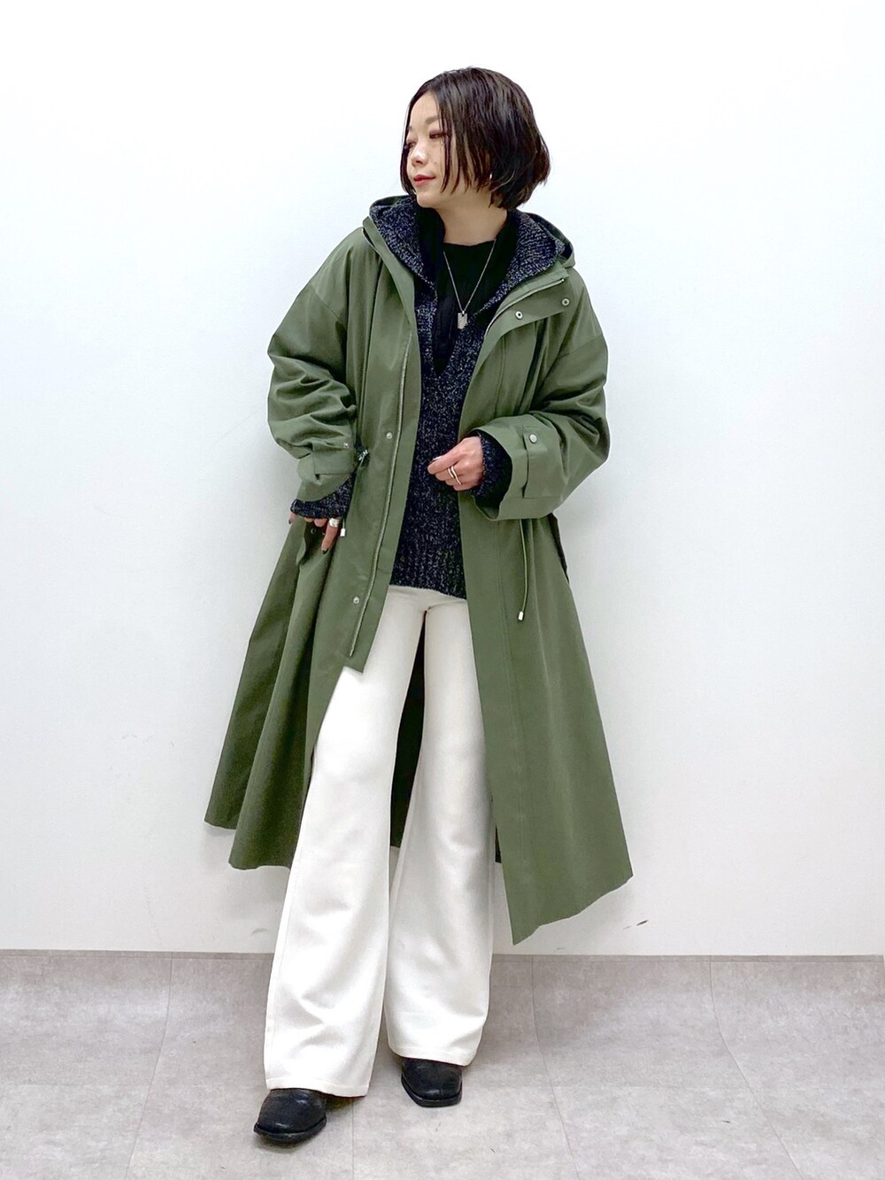 グリーン系のモッズコート、ホワイト系のスラックス、ブラック系のシューズを着用したレディースの冬コーディネートの3枚目の写真