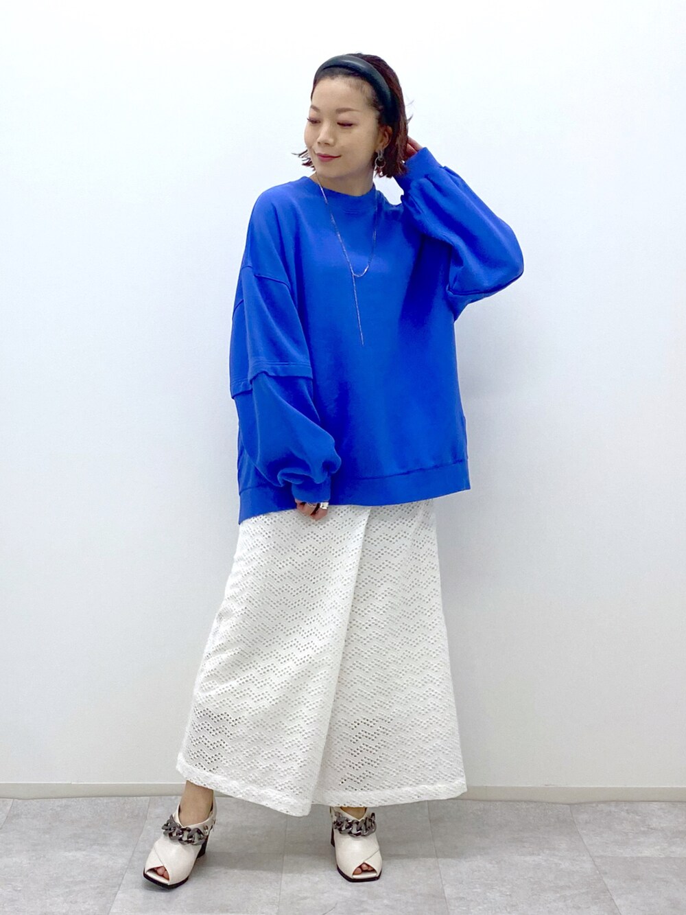 ブルー系のスウェット、ホワイト系のスカート、ホワイト系のパンプスを着用したレディースの冬コーディネートの4枚目の写真