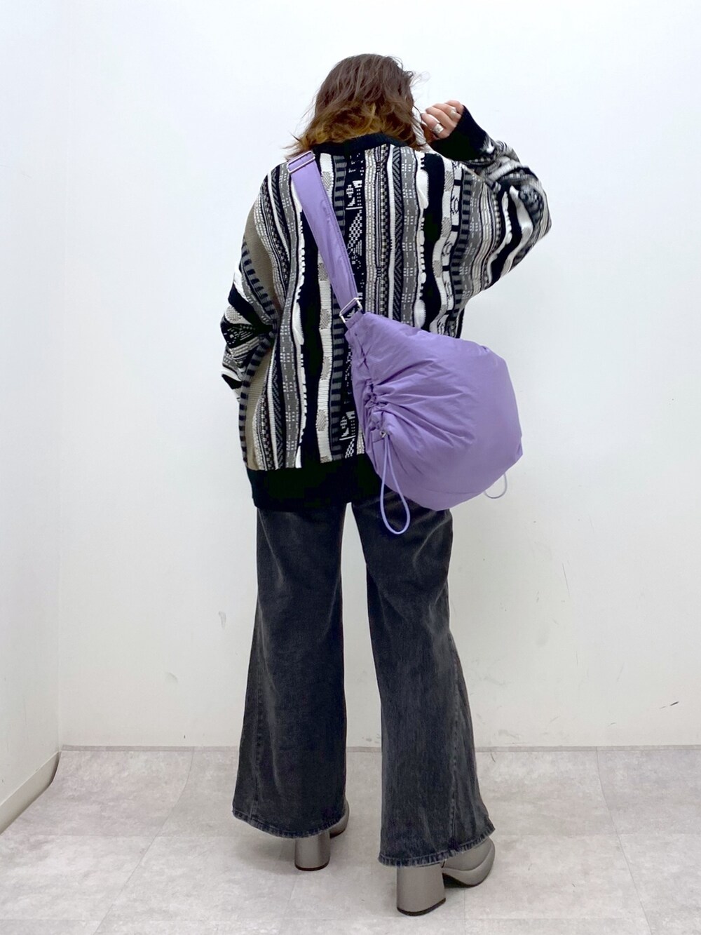 ブラック系のニット/セーター、ブラック系のデニムパンツ、パープル系のショルダーバッグを着用したレディースの秋コーディネートの4枚目の写真