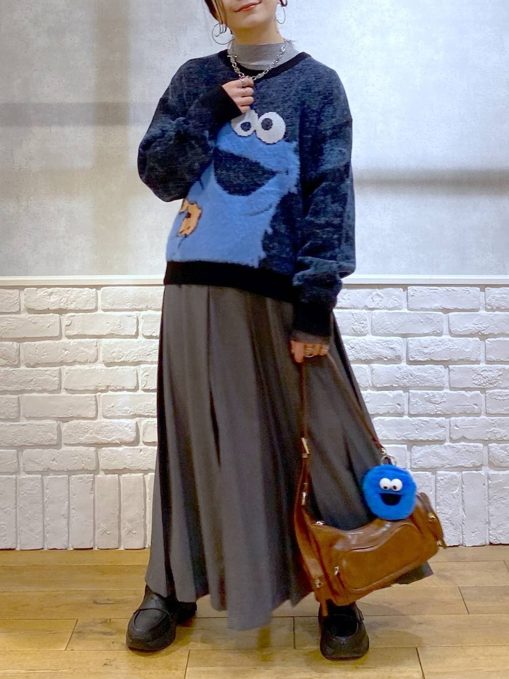 ブラック系のローファー、グレー系のスカート、ブラウン系のショルダーバッグを着用したレディースの冬コーディネートの3枚目の写真