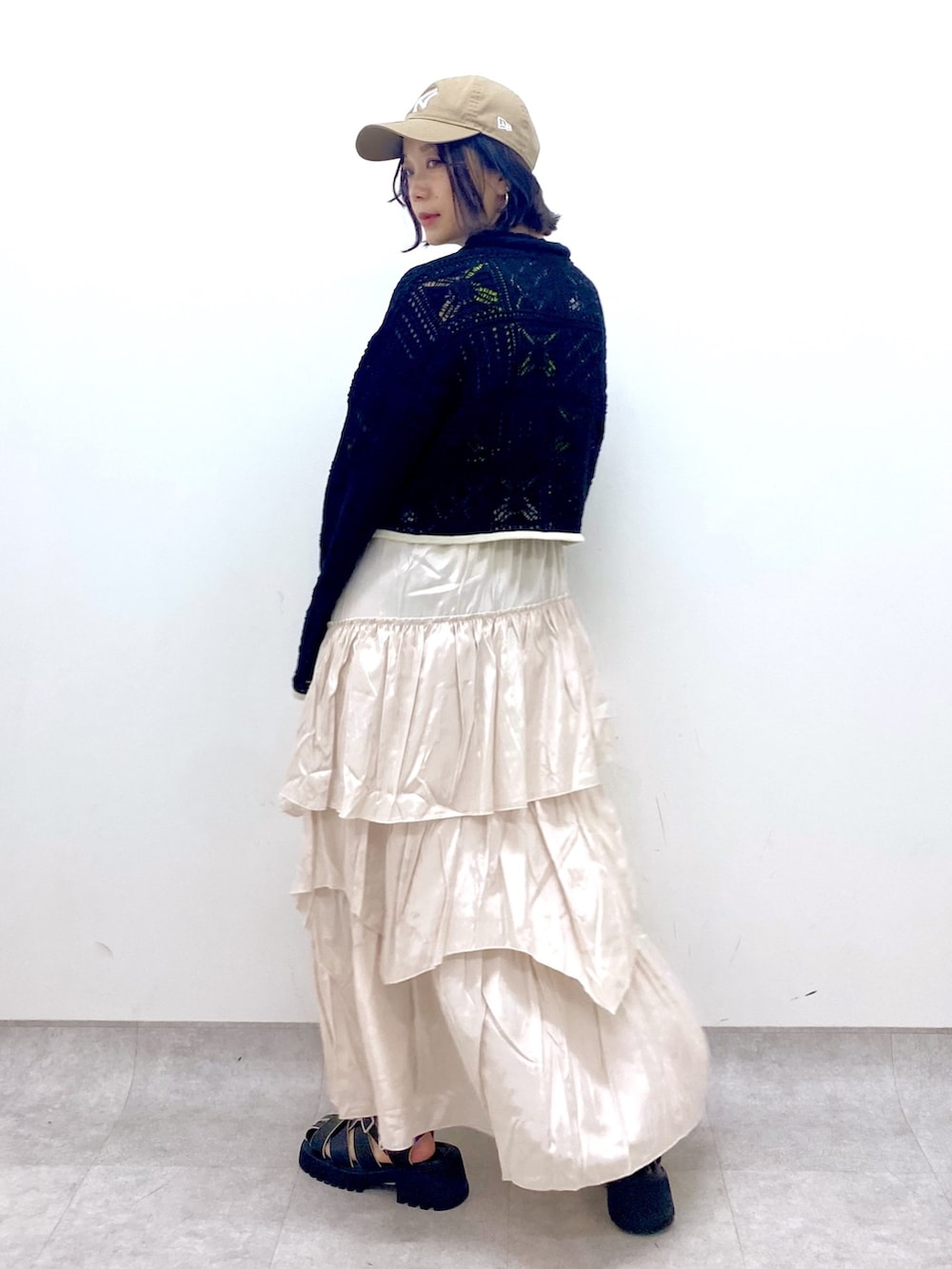 ホワイト系のスカート、ブラック系のサンダル、ブラック系のカーディガン/ボレロを着用したレディースの春コーディネートの3枚目の写真