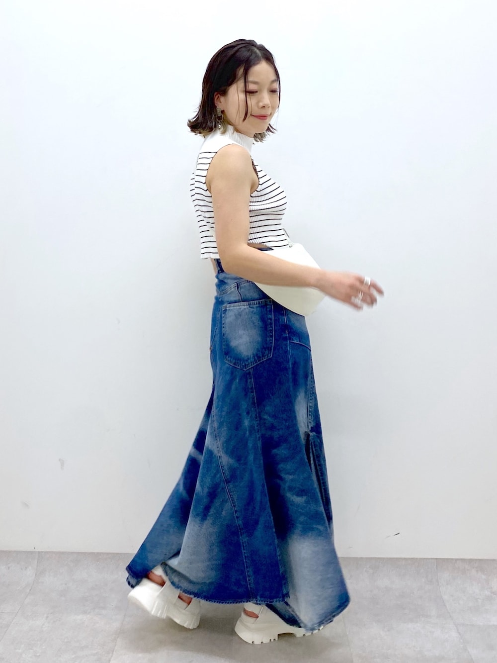 ホワイト系のショルダーバッグ、ブルー系のスカート、ホワイト系のTシャツ/カットソーを着用したレディースの夏コーディネートの3枚目の写真
