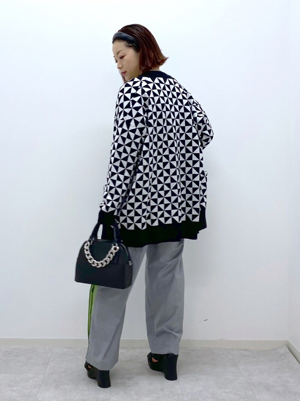 ホワイト系のカーディガン/ボレロ、グレー系のスラックス、ブラック系のショルダーバッグを着用したレディースの春コーディネートの3枚目の写真