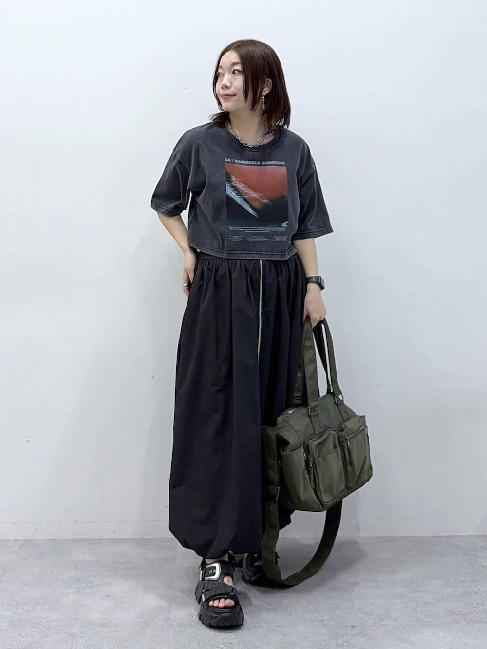 グリーン系のボストンバッグ、ブラック系のサンダル、ブラック系のスカートを着用したレディースの春コーディネートの3枚目の写真