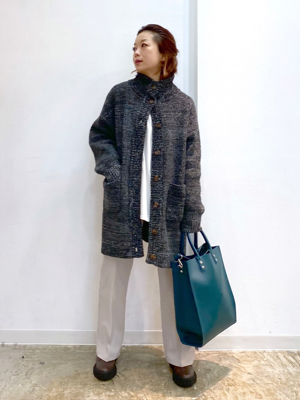 ホワイト系のTシャツ/カットソー、ブラック系のニット/セーター、グリーン系のトートバッグを着用したレディースの冬コーディネートの2枚目の写真