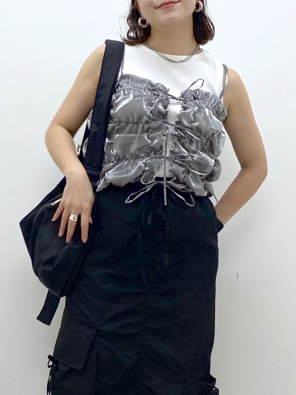 ブラック系のスニーカー、ブラック系のスカート、ブラック系のショルダーバッグを着用したレディースの夏コーディネートの2枚目の写真