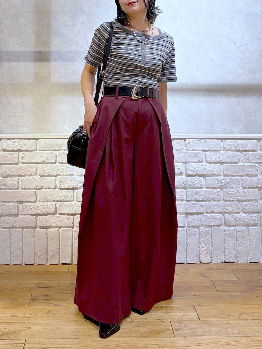 ブラック系のショルダーバッグ、レッド系のスラックス、グレー系のTシャツ/カットソーを着用したレディースの夏コーディネートの3枚目の写真