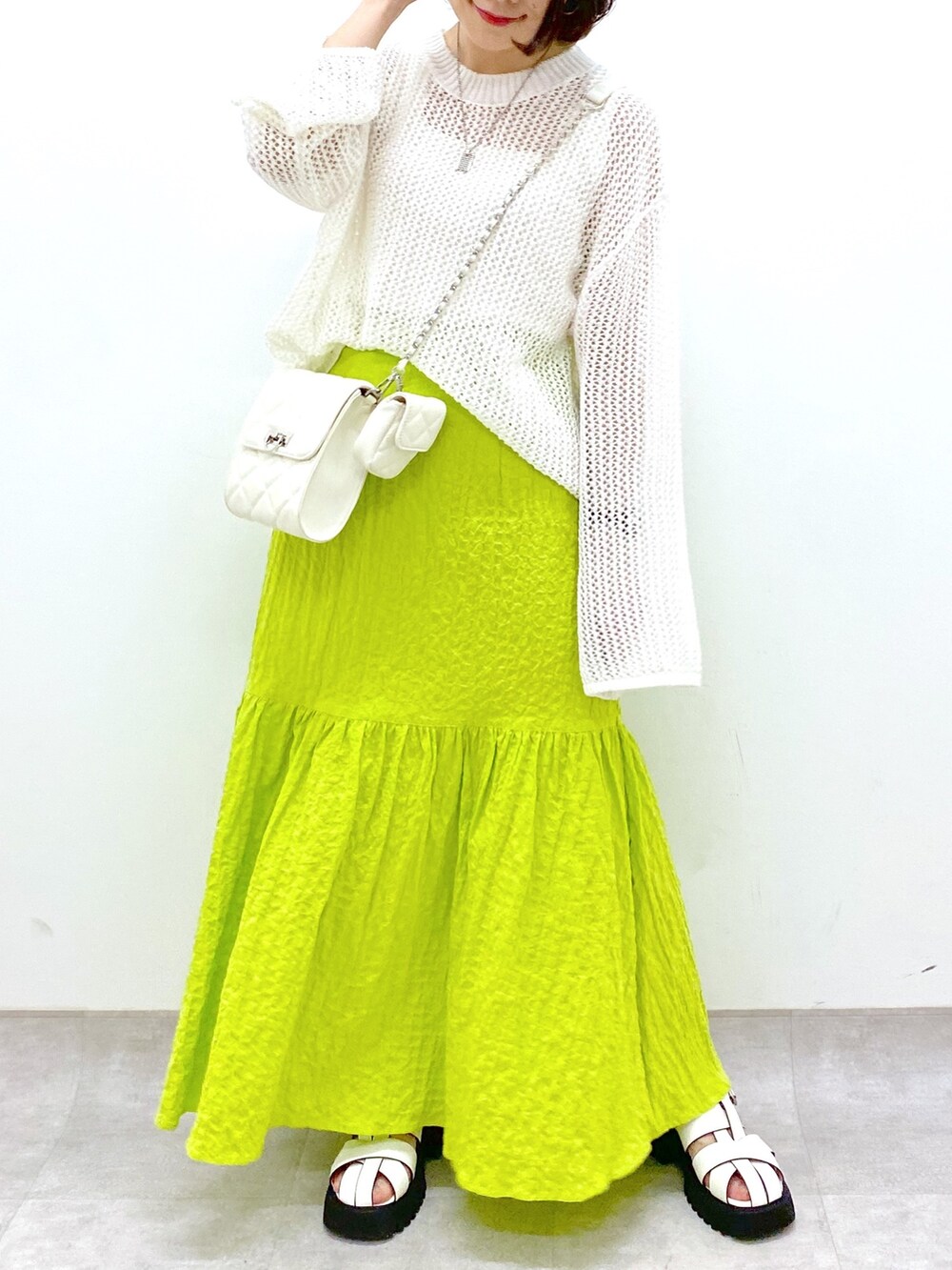 イエロー系のスカート、ホワイト系のバッグ、ホワイト系のトップスを着用したレディースの春コーディネートの4枚目の写真