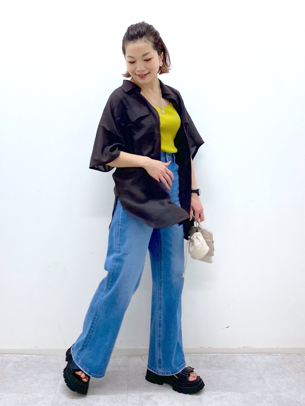 ブルー系のパンツ、イエロー系のタンクトップ、ベージュ系のショルダーバッグを着用したレディースの夏コーディネートの2枚目の写真