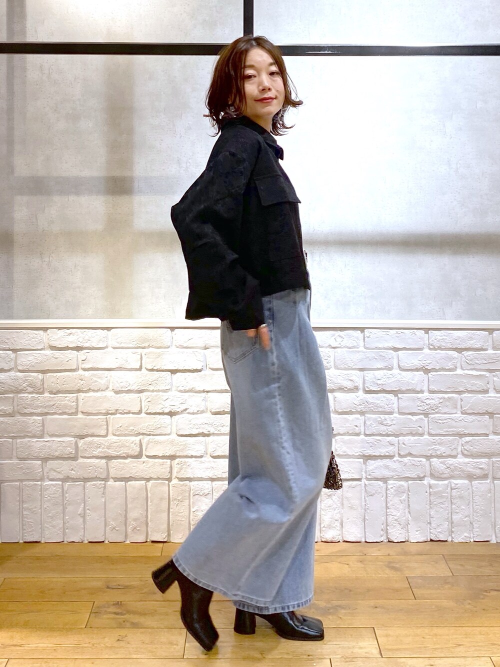 ブラック系のシャツ/ブラウス、ブルー系のデニムパンツ、ブルー系のショルダーバッグを着用したレディースの冬コーディネートの7枚目の写真