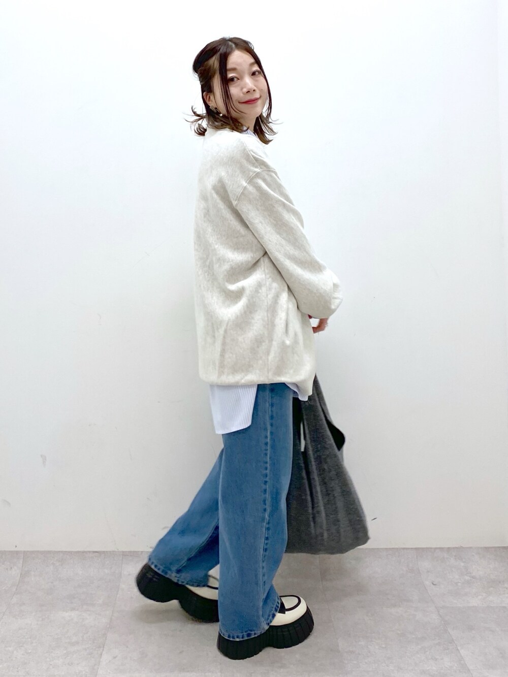 ベージュ系のスウェット、ブルー系のデニムパンツ、ブラック系のトートバッグを着用したレディースの冬コーディネートの5枚目の写真