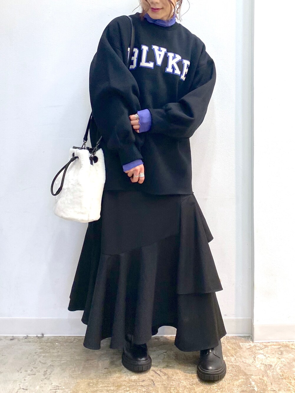 ブラック系のスカート、ブラック系のブーツ、ホワイト系のショルダーバッグを着用したレディースの秋コーディネートの3枚目の写真