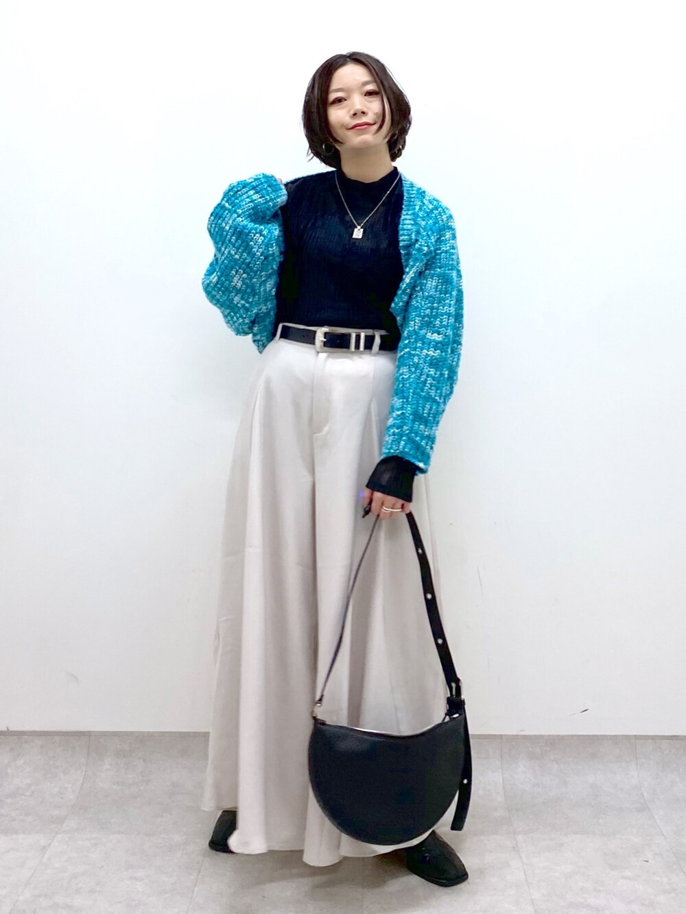 ベージュ系のスラックス、ブラック系のトップス、ブルー系のカーディガン/ボレロを着用したレディースの冬コーディネートの4枚目の写真