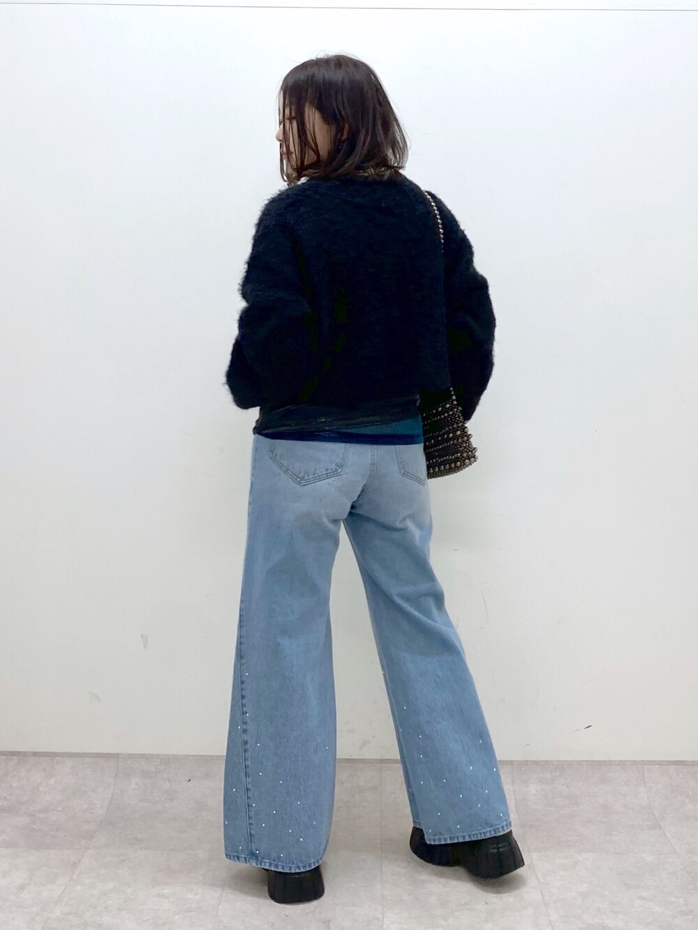 ブラック系のニット/セーター、ブルー系のデニムパンツ、ホワイト系のローファーを着用したレディースの冬コーディネートの5枚目の写真