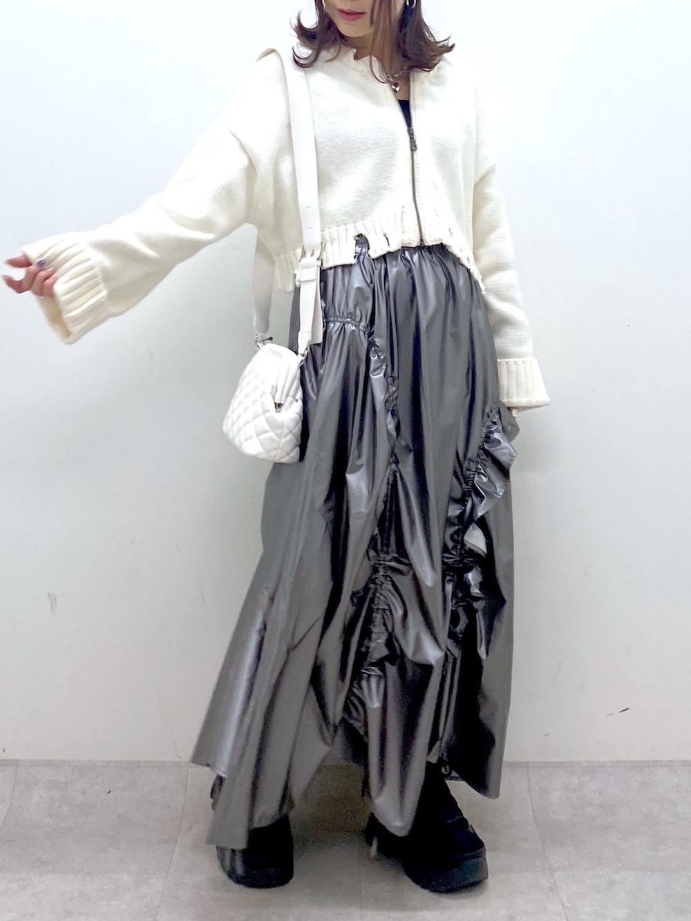 ホワイト系のニット/セーター、シルバー系のスカート、ホワイト系のショルダーバッグを着用したレディースの冬コーディネートの8枚目の写真