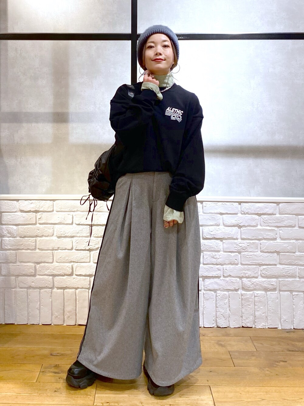 ブラック系のスウェット、グリーン系のショルダーバッグ、ブラック系のスラックスを着用したレディースの秋コーディネートの9枚目の写真