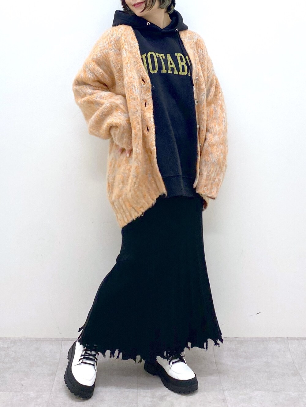 ブラック系のトップス、オレンジ系のカーディガン/ボレロ、ブラック系のスカートを着用したレディースの冬コーディネートの4枚目の写真