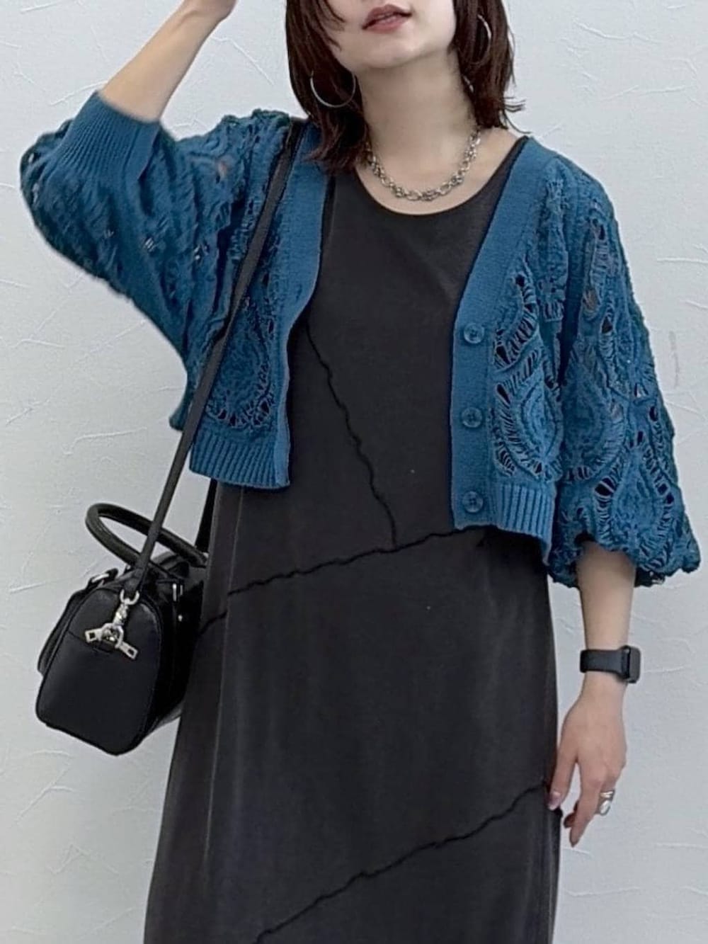 ブラック系のワンピース、ブルー系のカーディガン/ボレロ、ブラック系のボストンバッグを着用したレディースの春コーディネートの2枚目の写真
