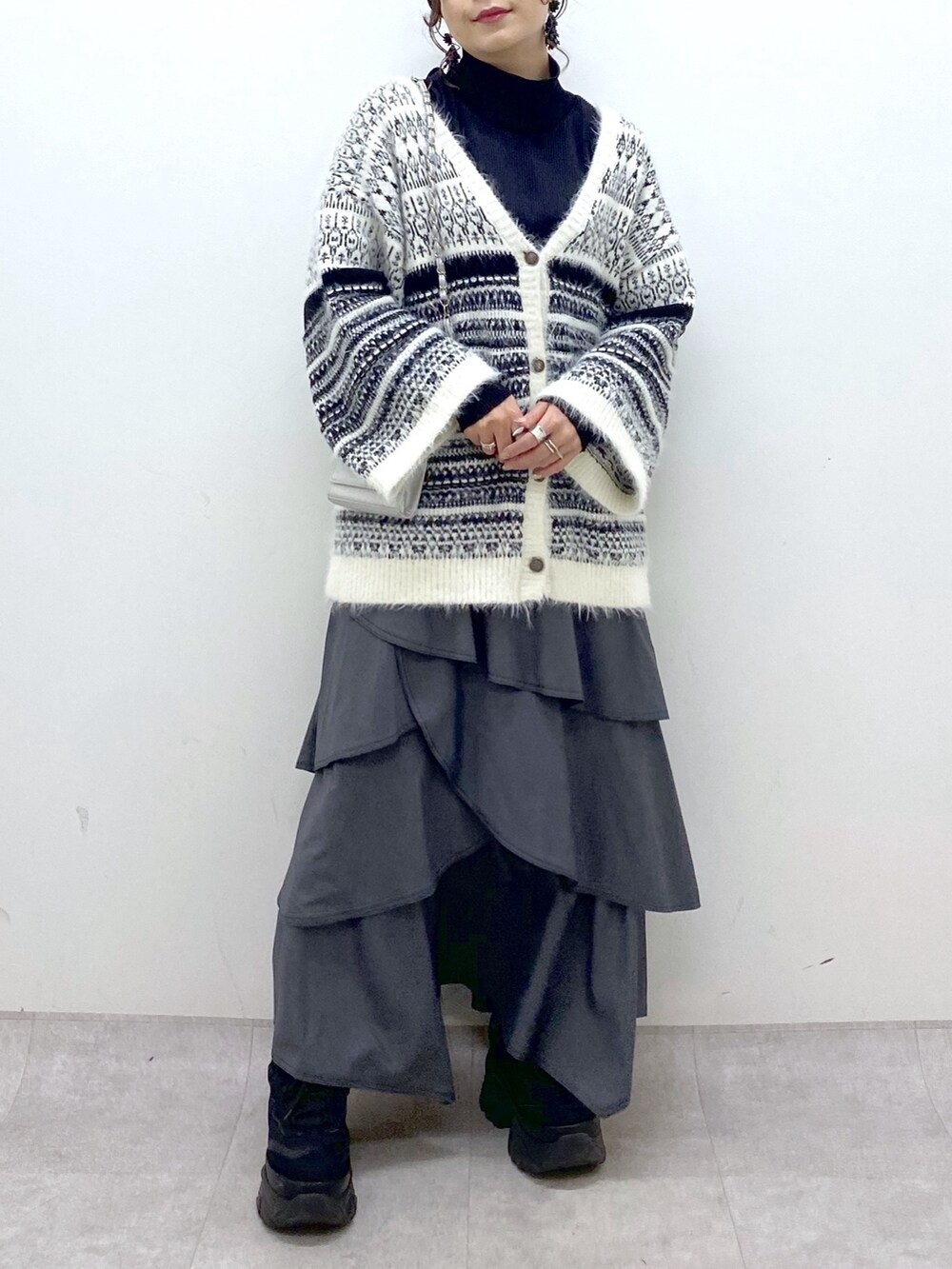 ホワイト系のカーディガン/ボレロ、グレー系のスカート、ブラック系のスニーカーを着用したレディースの冬コーディネートの8枚目の写真