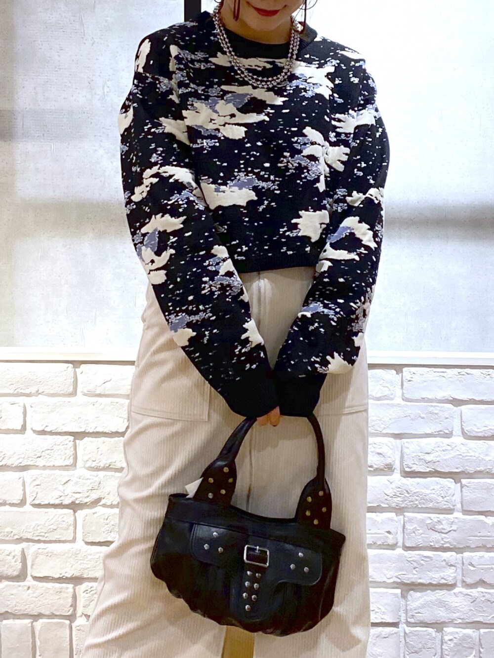 ブラック系のニット/セーター、ブラック系のハンドバッグ、ブラック系のブーツを着用したレディースの冬コーディネートの2枚目の写真