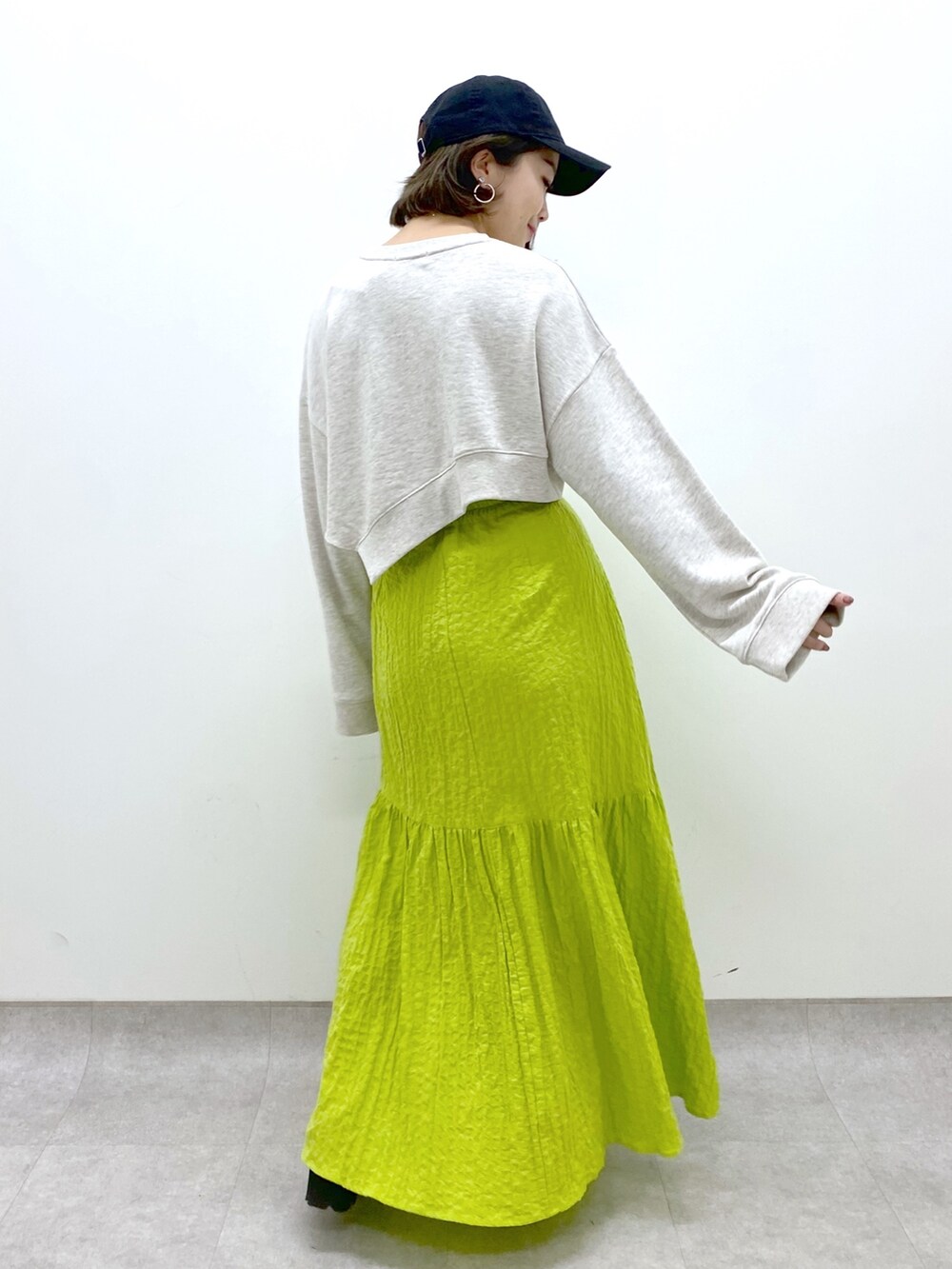 イエロー系のスカート、ベージュ系のトップス、ブラック系のローファーを着用したレディースの春コーディネートの4枚目の写真