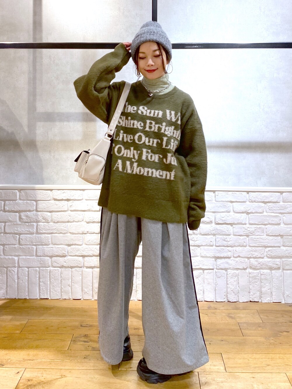 ブラック系のスラックス、グリーン系のTシャツ/カットソー、ブラック系のブーツを着用したレディースの冬コーディネートの8枚目の写真
