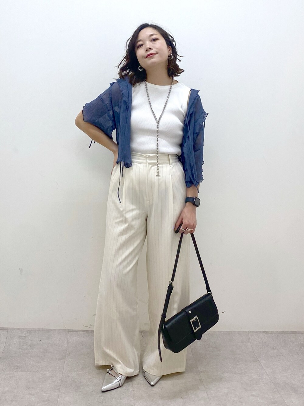ホワイト系のスラックス、ブラック系のハンドバッグ、シルバー系のパンプスを着用したレディースの夏コーディネートの4枚目の写真