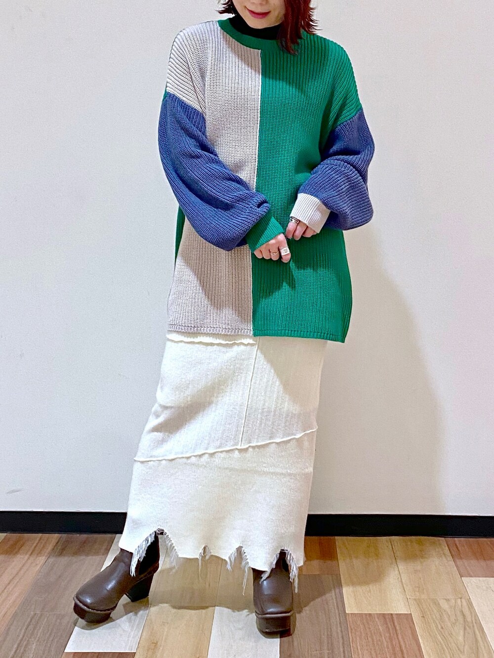 ブラウン系のブーツ、ホワイト系のスカート、グリーン系のニット/セーターを着用したレディースの冬コーディネートの5枚目の写真