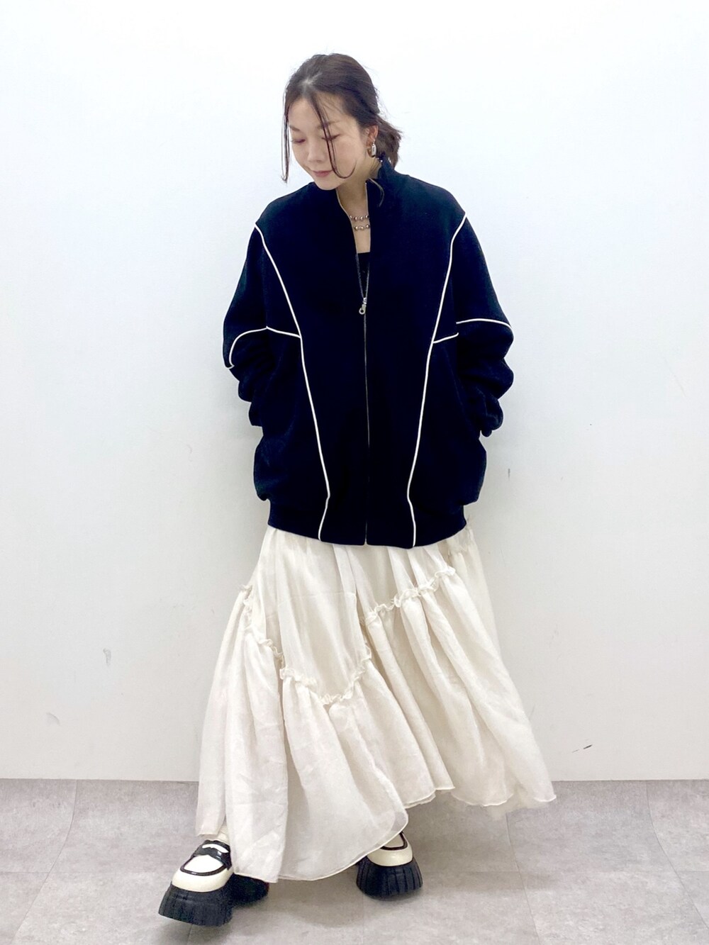 ブラック系のスウェット、ホワイト系のスカート、ホワイト系のローファーを着用したレディースの春コーディネートの4枚目の写真