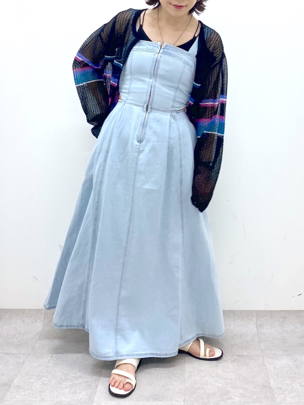 ブルー系のジャンパースカート、ホワイト系のサンダル、ブラック系のカーディガン/ボレロを着用したレディースの春コーディネートの4枚目の写真