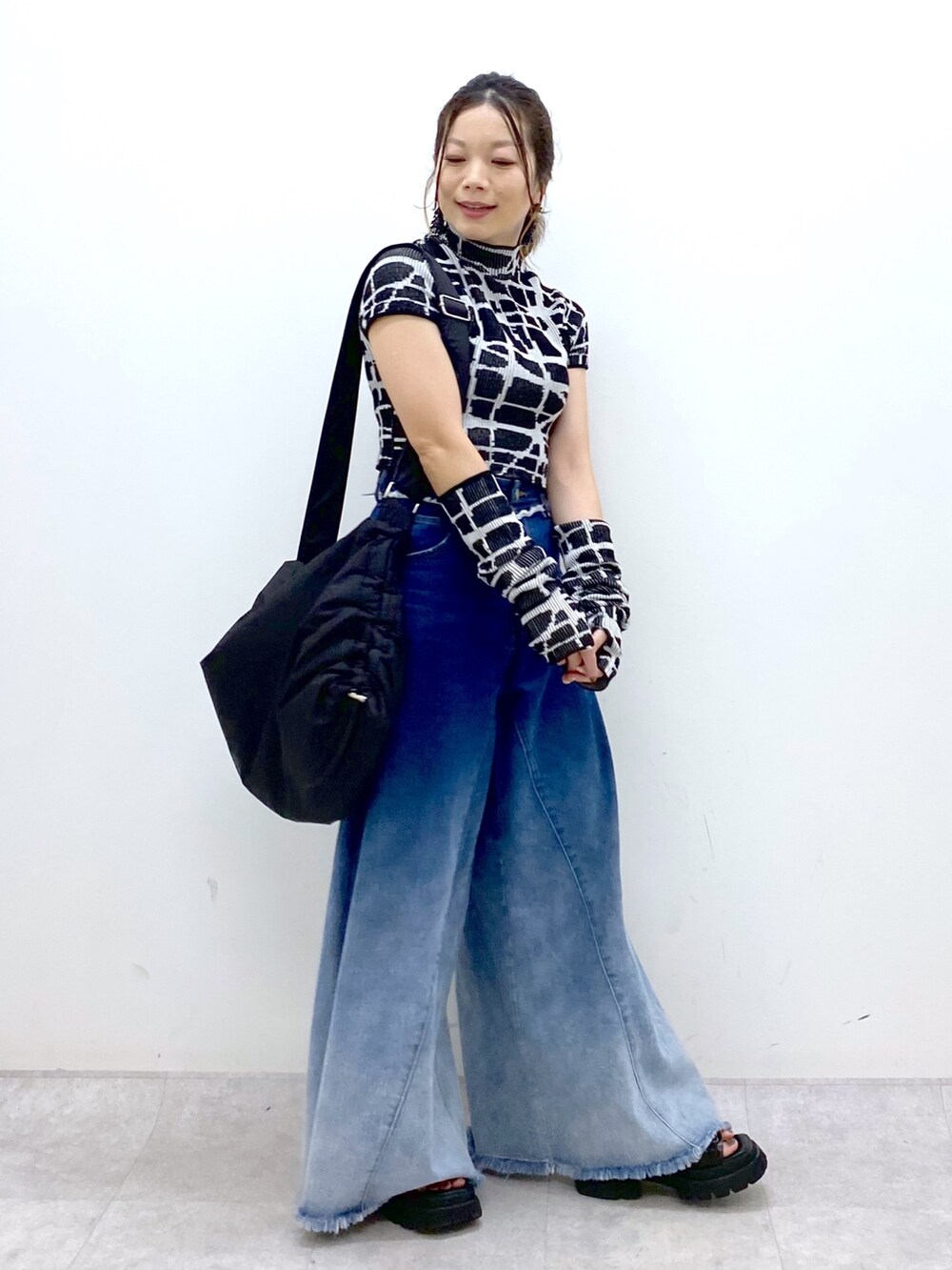 ブルー系のデニムパンツ、ブラック系のニット/セーター、ブラック系のショルダーバッグを着用したレディースの夏コーディネートの3枚目の写真