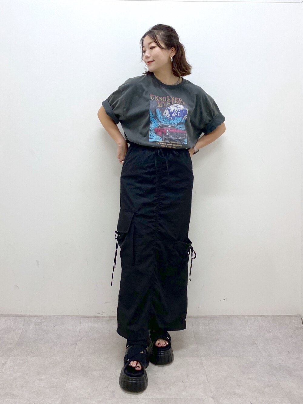 グレー系のTシャツ/カットソー、ブラック系のスカート、ブラック系のスニーカーを着用したレディースの夏コーディネートの9枚目の写真