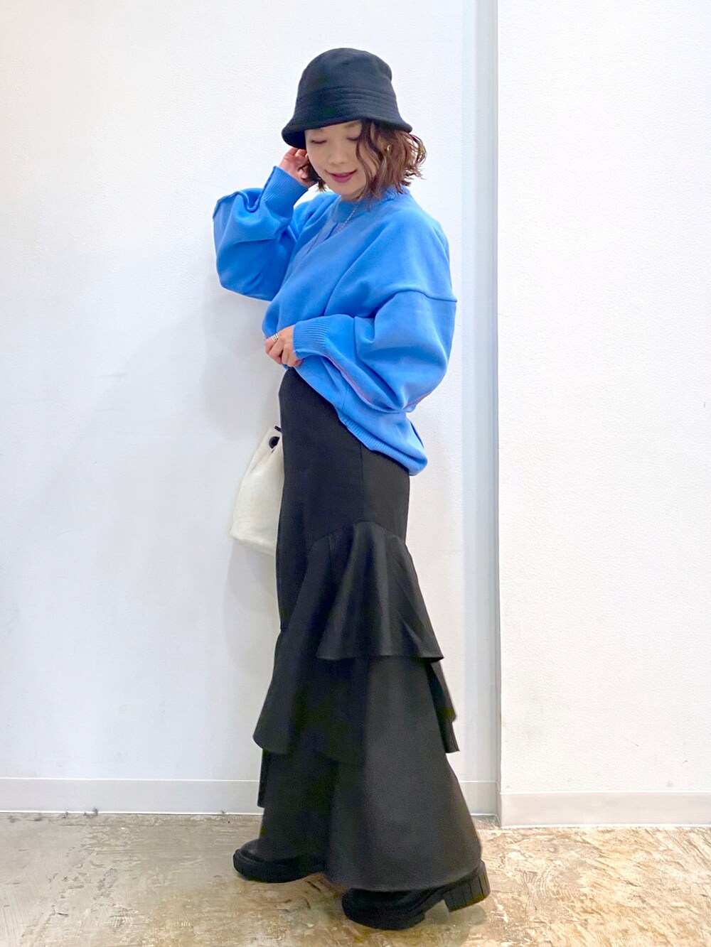 ホワイト系のショルダーバッグ、ブルー系のニット/セーター、ブラック系のスカートを着用したレディースの秋コーディネートの2枚目の写真